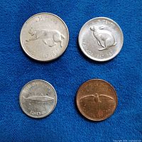 Four Canadian Centennial coins obverse wildlife side displayed on blue cloth