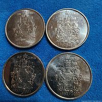 Four 1952-2002 Canadian 50-cent coins on blue cloth