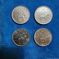 Four 1973 Canada 25-cent RCMP coins on blue cloth