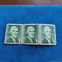 Full view of the three connected stamps on blue background