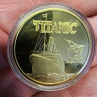 Obverse of gold-tone Titanic commemorative coin in capsule held in hand