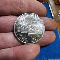 Obverse view of Whistler BC Canada All Seasons Resort one-dollar token in hand