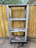 Full view of the 4-tier wooden shelf against fence