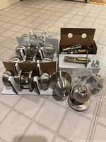 Group of boxed door knob sets, loose privacy knob set, and hardware spread on floor