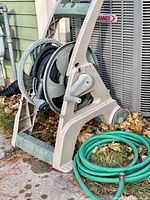 Hose reel cart with black hose and nozzle, green hose beside