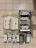 All components laid out: outlets, wall plates, metal box, Decora switch