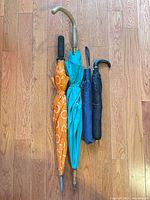 All four umbrellas side by side folded on floor