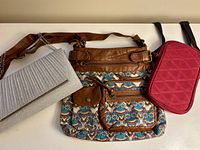 All three bags laid out: silver clutch, brown crossbody, magenta phone pouch