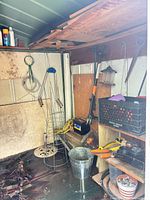 Overall view of shed right side with tools, cages, bucket, shelf, lumber