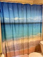 Full view of beach-themed shower curtain hanging in bathroom