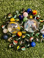 Group of marbles showing two large shooters and numerous small marbles on turf