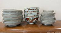 Three stacks of porcelain dinnerware showing quantity and variety