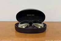 Sunglasses in open black Michael Kors case, frontal view