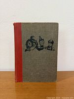 Front cover showing grey cloth, red spine, black character silhouettes