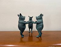 Front view of bronze sculpture showing three pigs dancing in circle