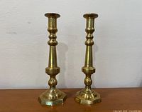 Front view of brass candlestick pair on wood surface