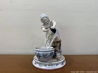Front view of figurine showing woman washing boy in basin, inscription visible