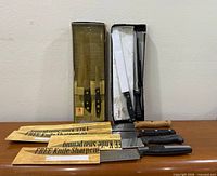 Overall lot with boxed knives, honing steel, four loose knives and cardboard knife sleeves visible