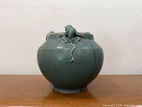 Front view of jade green ceramic vase with monkey figure and tail detail