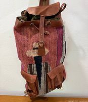 Front view of backpack showing woven motif, leather flap and straps
