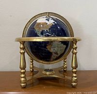 Front view of gemstone inlaid globe on brass stand