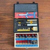 Open plastic case showing soldering iron, tips, sponge and accessories plus open router bit box below