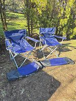 Two assembled blue folding chairs and two carry bags displayed outdoors