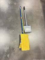 Broom, mop and dustpan laid side by side on floor