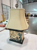 Front view of lamp showing shade, scenic base panel, finial