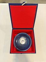 Open presentation box showing porcelain dish seated inside red-lined interior