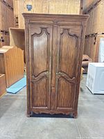 Front view of closed armoire showing carved doors and finish