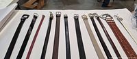 All 12 belts laid flat showing buckles, colors and widths
