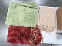 Top view of green fleece, beige woven, red woven throws