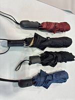 Four folding umbrellas laid horizontally to show full view of each item