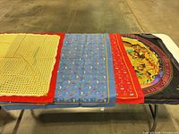 All four scarves laid flat on table showing patterns and colours