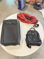 Overview of three bags: Victorinox suitcase, Tumi tote, red packable duffel