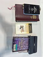 All four items laid out: burgundy leather Rainbow Study Bible with attached promise booklet on top, pocket dictionary center, boxed pocket-size Bible with snap case bottom