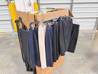 Overview of garments hanging on box, showing variety of skirts and trousers