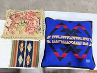 Group shot showing floral needlepoint pillow, woven runner and one Pendleton geometric pillow