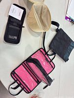 All four items laid out: black zip pouch, beige vanity case (open), black crossbody, pink kate spade organizer (open)