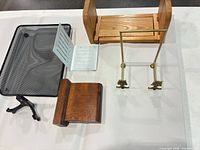 Group shot showing book rack ends, mesh tray, white bracket, one brass easel, one wooden bookend, black stand