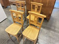 Front angled view of four matching ladder-back chairs