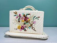 Front view of complete cheese dish showing floral decoration and handle