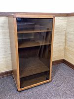 Front view of oak-finish stereo cabinet with glass door and casters