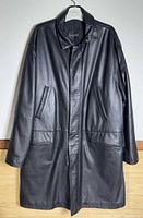 Front view of black leather coat hanging, showing overall style and length