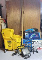 Full lot view showing mop bucket, vacuum in box, steam cleaner box, work light