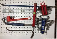 Overall layout of crowbars, level, pipe wrench, adjustable wrench, and two wrench sets on pegboard