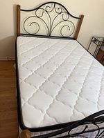 Overall view of bed showing headboard scroll design, mattress, frame and wood posts