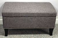 front view of gray upholstered storage ottoman bench showing full shape and upholstery