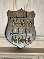 Full view of shield-shaped rack holding 12 gold-tone spoons